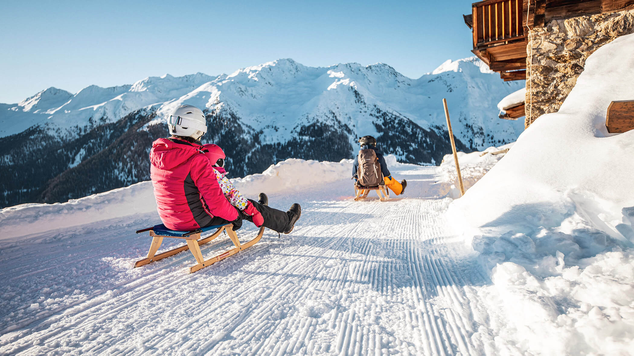 Eine Familie beim Rodeln auf der Pertinger Alm - Bad Bergfallerhof
