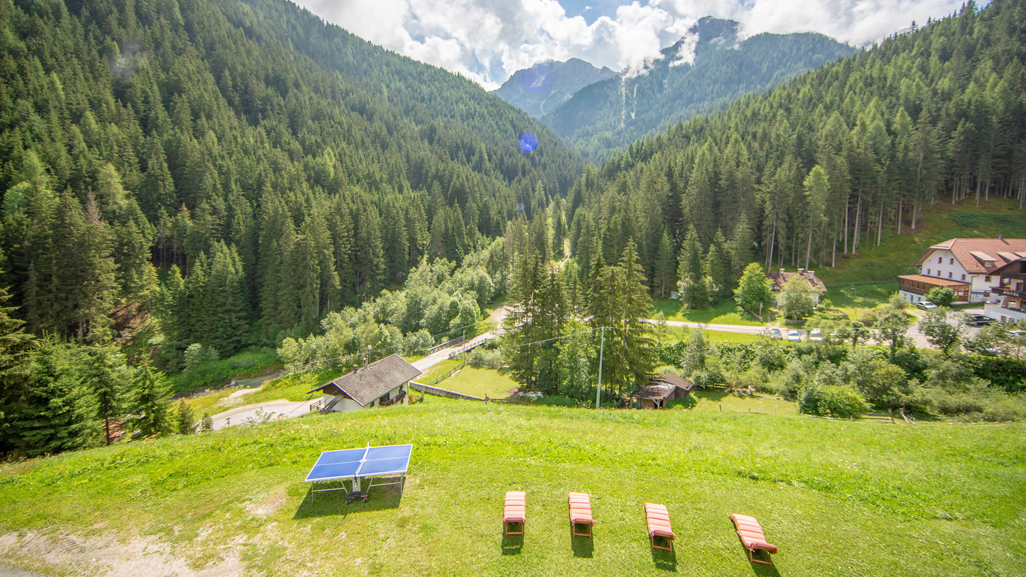 Grüne Wiese mit viel Liegestühlen und einem Tischtennis-Tisch - Bad Bergfallerhof