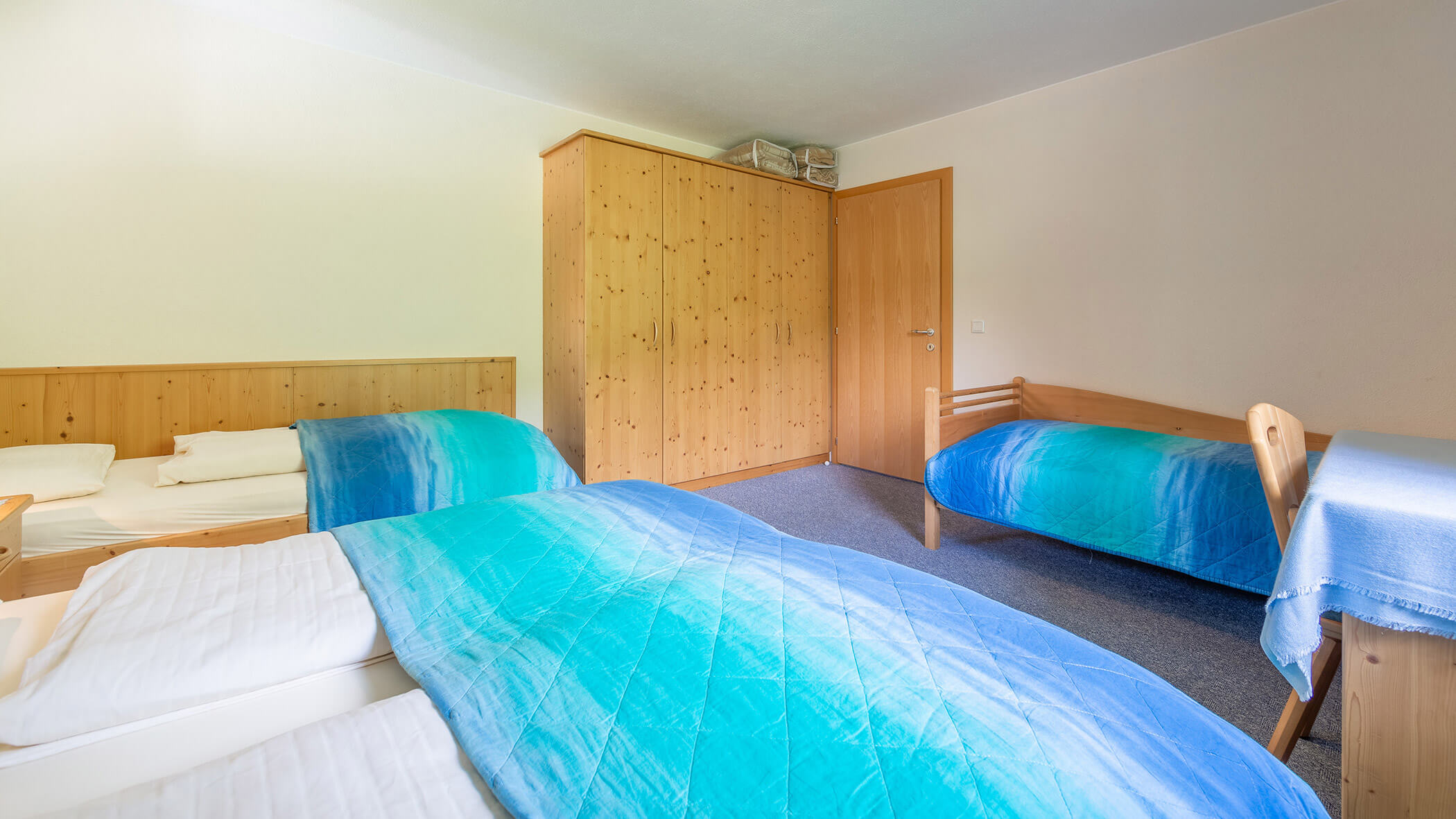 Schlafzimmer mit einem Doppelbett und zwei Einzelbetten in der Ferienwohnung Typ B - Bad Bergfallerhof