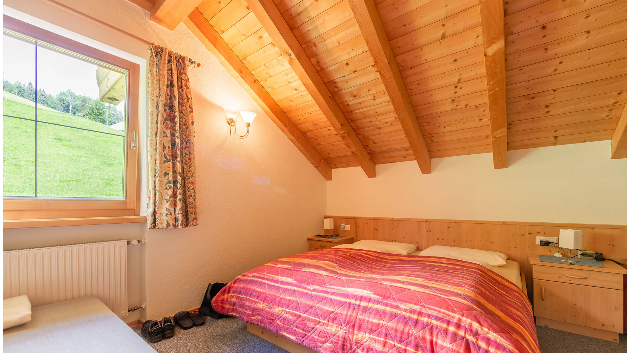 Schlafzimmer mit Doppelbett und Fenster daneben in der Ferienwohnung Typ A - Bad Bergfallerhof